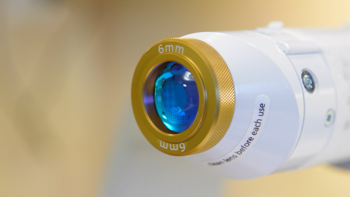Close-up of the Aerolase Neo Elite handpiece: the gold-ringed 6mm precision lens of the medical laser.